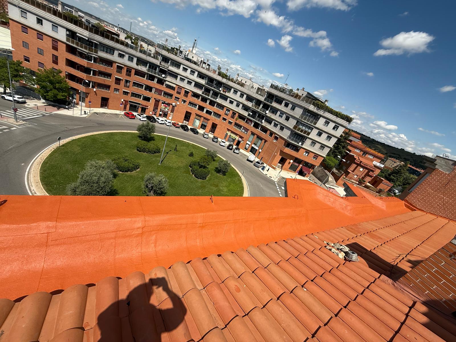 Cubierta impermeabilizada con peto curvo en color naranja sobre los tejados de Madrid, ejecutada por Aislamientos de Poliuretano CV